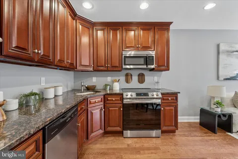 a kitchen with granite countertop a stove top oven microwave and cabinets