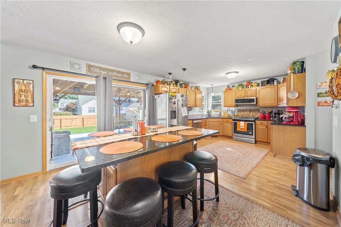 1951 Haines Road Madison, OH 44057 - Photo 13 of 44 Kitchen with appliances with stainless steel finishes, a textured ceiling, light wood-type flooring, and a breakfast bar area