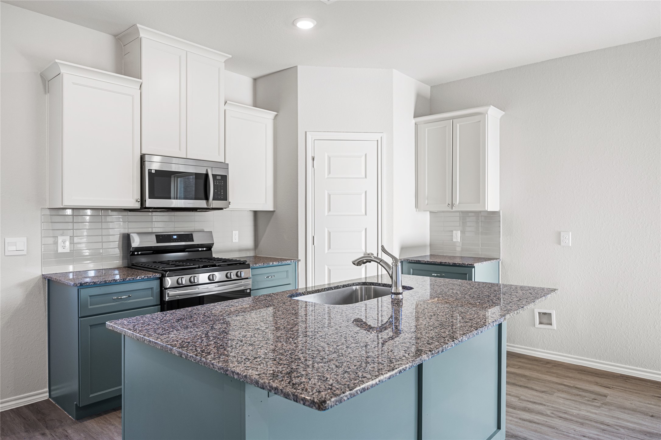 25799 John Wayne Court Splendora, TX 77372 - Photo 8 of 28 a kitchen with granite countertop a sink a stove and microwave
