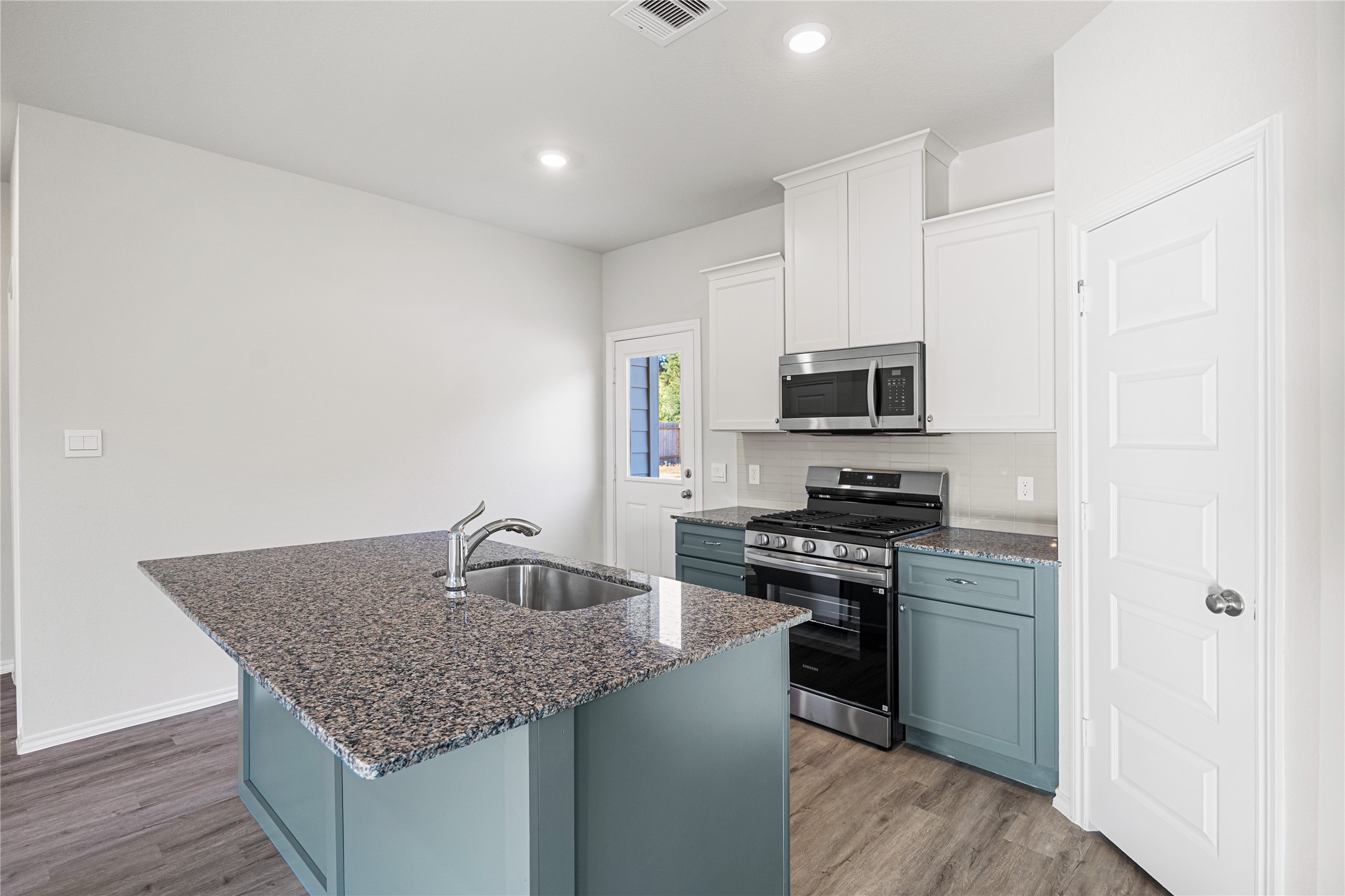 25799 John Wayne Court Splendora, TX 77372 - Photo 10 of 28 a kitchen with granite countertop stainless steel appliances and wooden floor