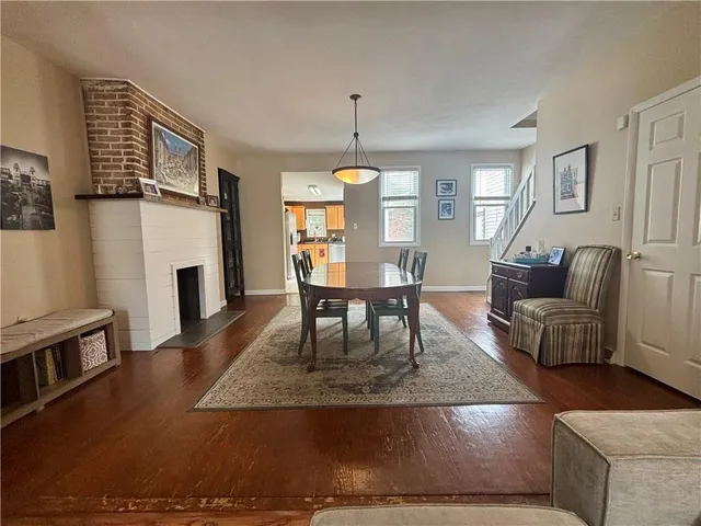 a living room with furniture a fireplace and a dining table with wooden floor
