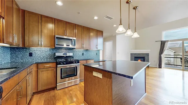 a kitchen with stainless steel appliances granite countertop a sink a stove and a wooden floors