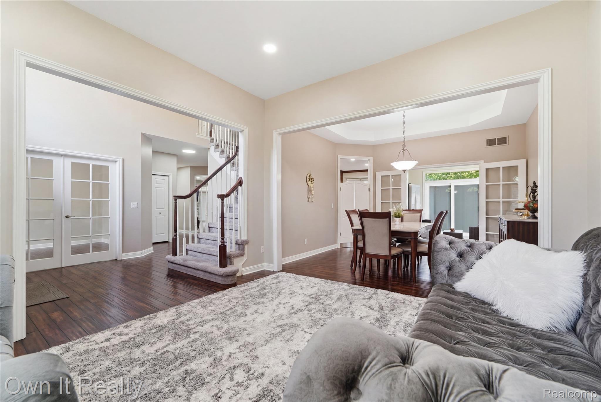 48280 Gladstone Road Canton, MI 48188 - Photo 9 of 59 Expansive main level featuring wood-finish flooring, a carpeted staircase with wood banisters, French doors, and a dining area with a tray ceiling and sliding glass doors