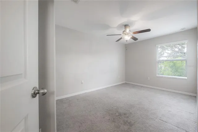 an empty room with a chandelier fan and windows