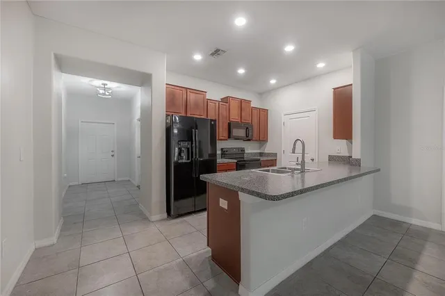 a view of kitchen with stainless steel appliances granite countertop refrigerator sink and stove