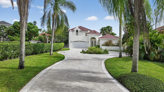 a view of a white house with a small yard and potted plants