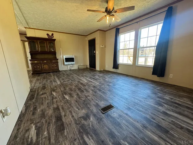 a view of a livingroom with wooden floor ceiling fan and window