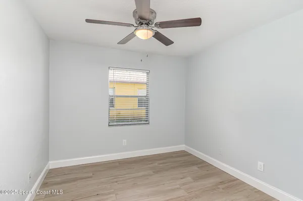 an empty room with a window and a fan