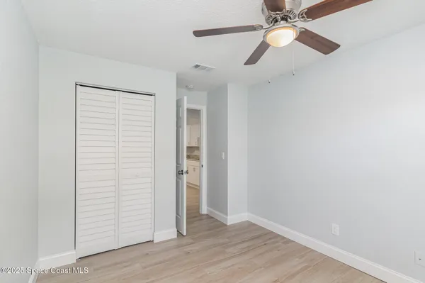 an empty room with wooden floor chandelier fan and closet