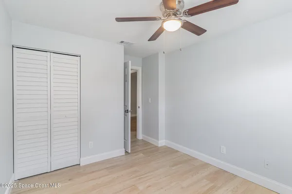 an empty room with closet and a ceiling fan