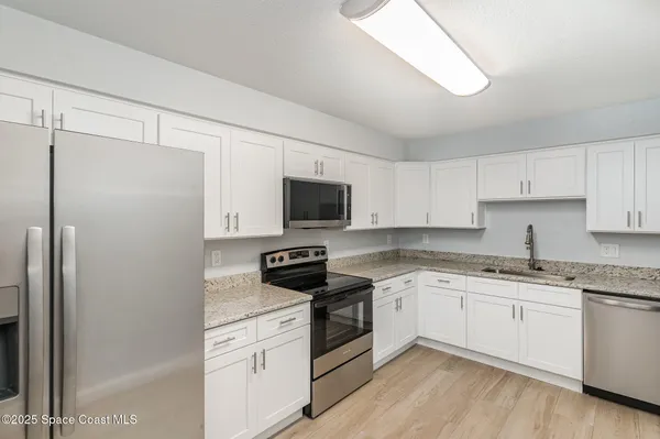 a kitchen with stainless steel appliances granite countertop white cabinets stove a sink and dishwasher