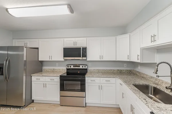 a kitchen with white cabinets and stainless steel appliances
