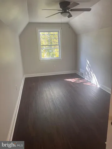 an empty room with wooden floor ceiling fan and windows