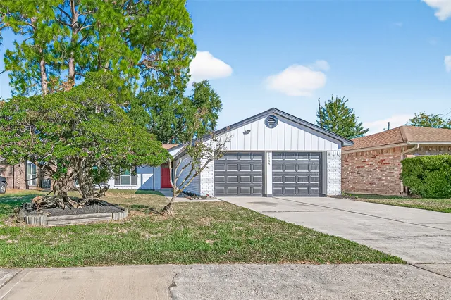 a view of a house with a yard and large tree