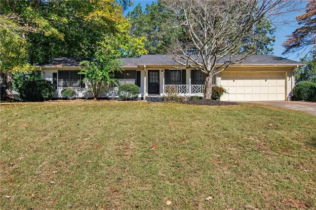 a front view of a house with a garden and tree