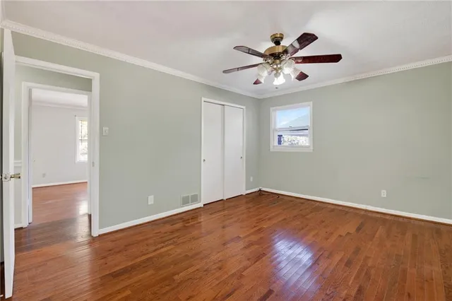 a view of an empty room with window and wooden floor