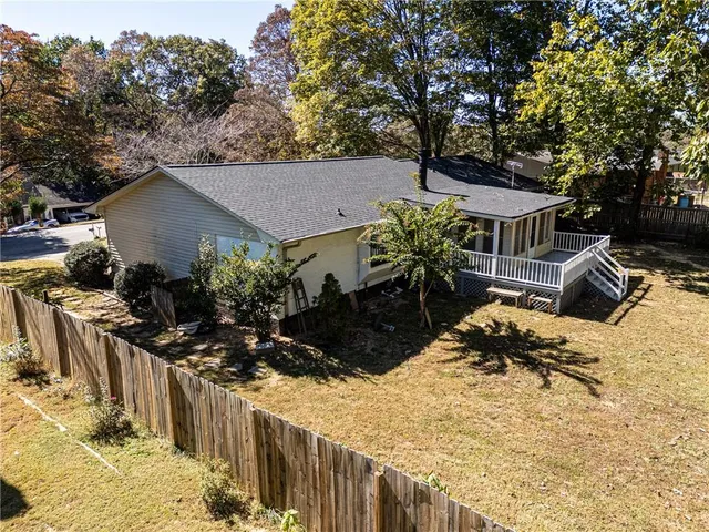 a view of house with yard outdoor seating and covered with trees