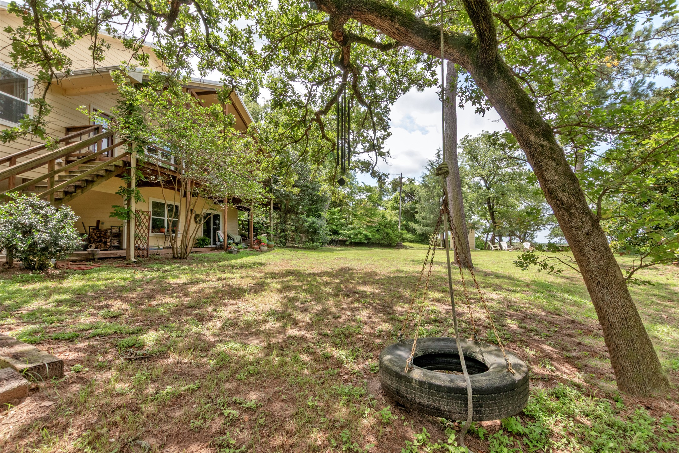 9997 Calhoun Road Bryan, TX 77808 - Photo 25 of 28 Mature trees shade a sloping lawn behind a multi-level wood structure.