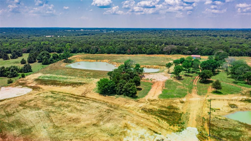1789 Brumelow Road Whitesboro, TX 76273 - Photo 25 of 30 Expansive rural landscape featuring multiple ponds, scattered mature trees, and a distant barn structure