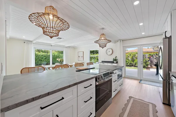 a kitchen with stainless steel appliances granite countertop a kitchen island a stove a refrigerator and white cabinets with wooden floor