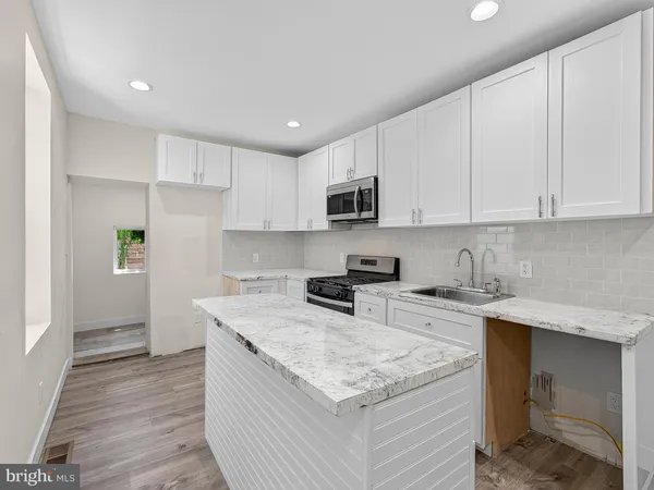 a kitchen with stainless steel appliances granite countertop a stove top oven a sink dishwasher and a refrigerator with wooden floor