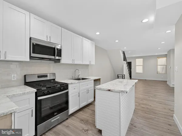 a kitchen with stainless steel appliances granite countertop a stove top oven a sink dishwasher and white cabinets with wooden floor