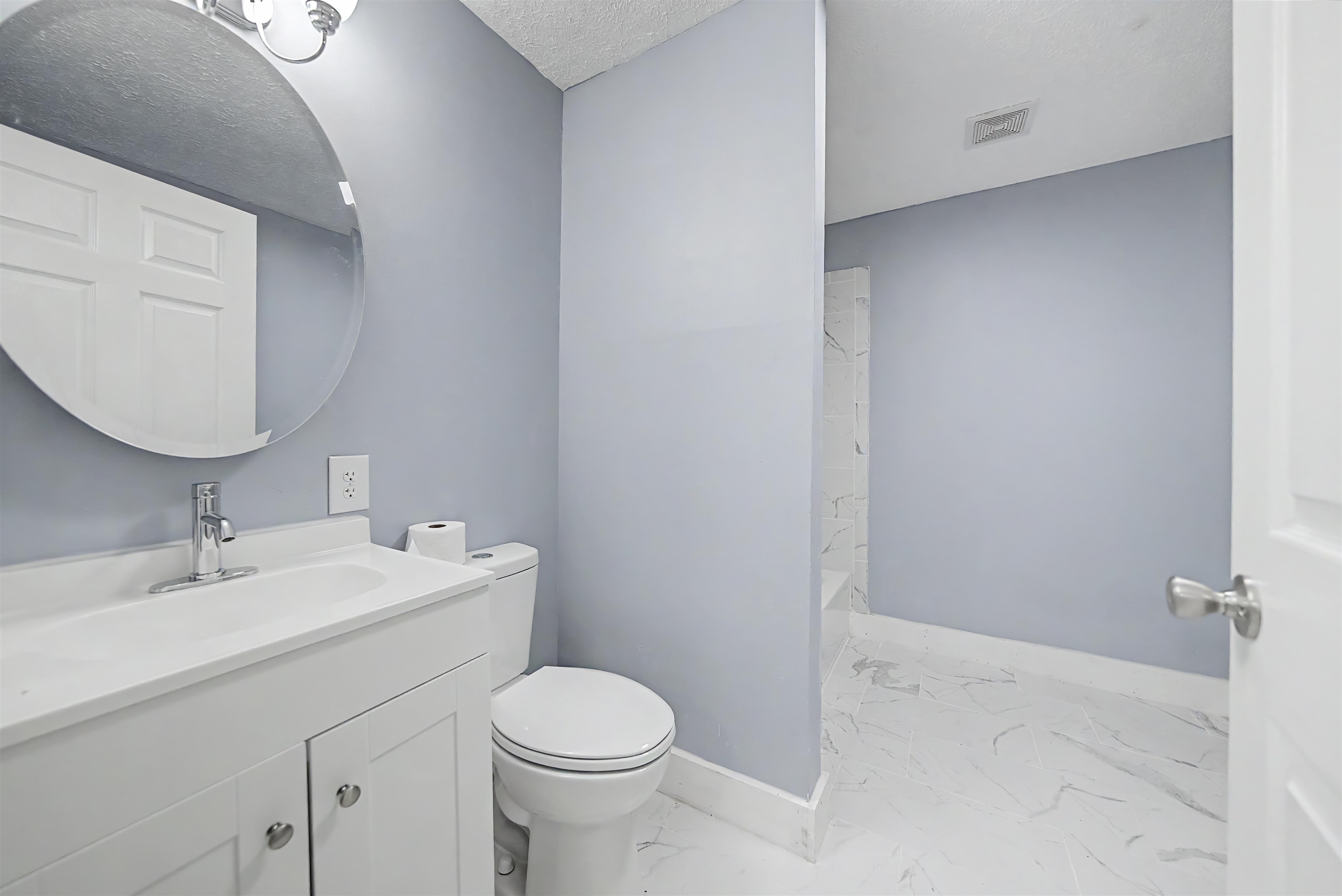 7437 Highway 45 Ramer, TN 38367 - Photo 33 of 36 Bathroom featuring a white vanity with integrated sink, chrome faucet, round wall mirror, and marble-look floor tiling