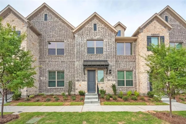 a front view of a house with a yard and large tree