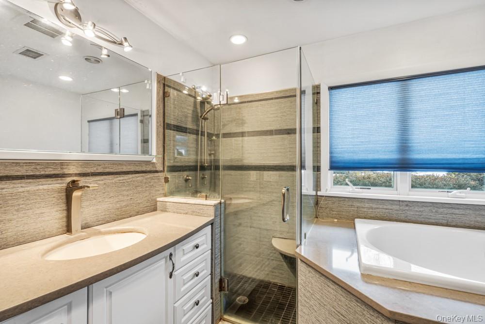 1 Virginia Road Syosset, NY 11791 - Photo 12 of 16 a bathroom with a granite countertop sink a large mirror and a bathtub