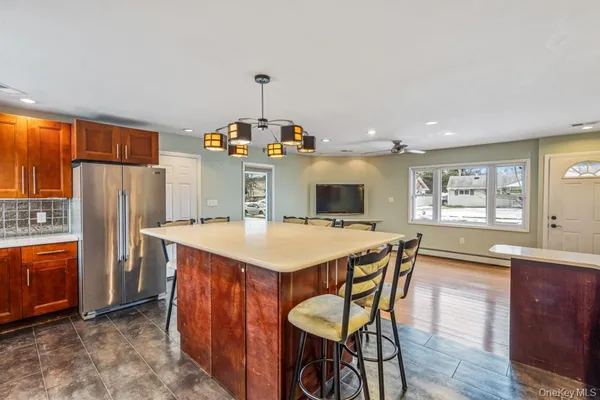 a kitchen with stainless steel appliances a sink a stove a refrigerator a dining table and chairs with wooden floor