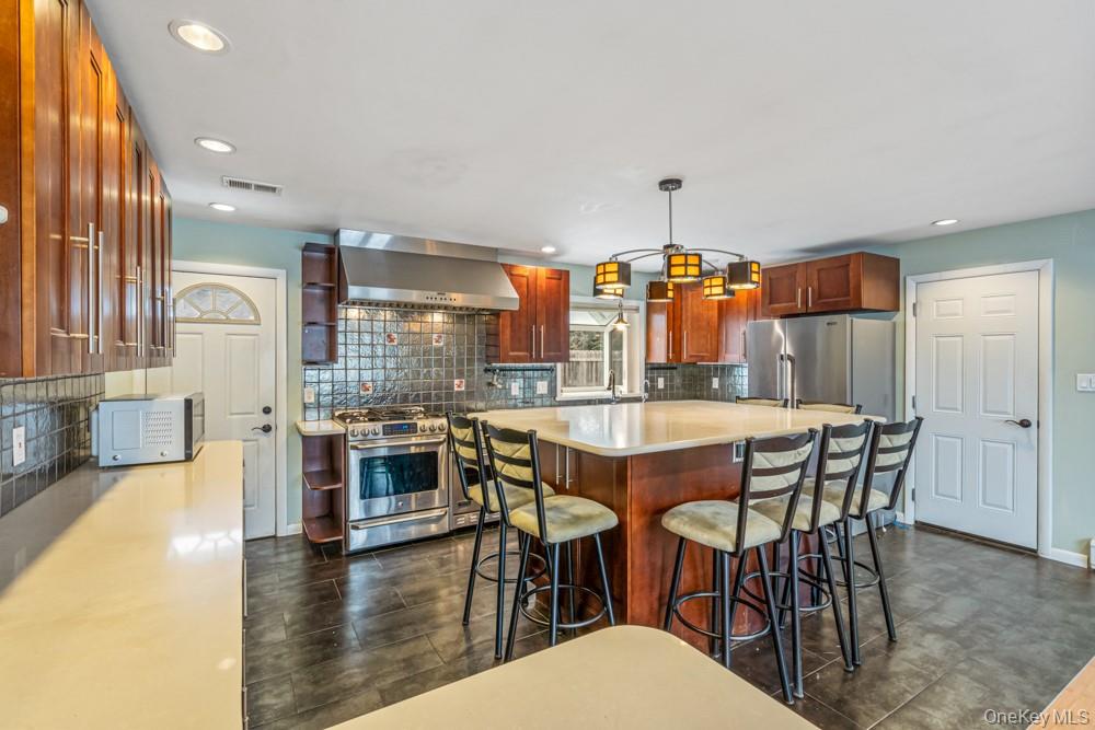 1 Virginia Road Syosset, NY 11791 - Photo 5 of 16 a dining room with stainless steel appliances kitchen island granite countertop a table and chairs in it