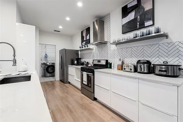 a kitchen with stainless steel appliances granite countertop a refrigerator a stove and a sink