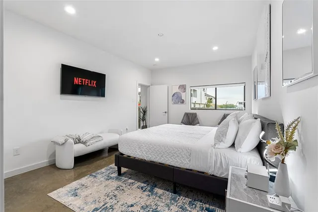 a bedroom with a bed a couch and a flat screen tv