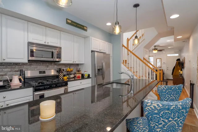 a kitchen with granite countertop a stove a sink and a refrigerator