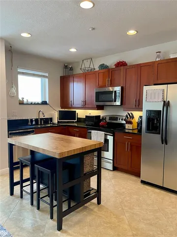 a kitchen with stainless steel appliances granite countertop a stove a refrigerator a sink a stove a dining table and chairs