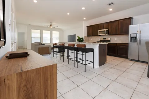 a large kitchen with stainless steel appliances a refrigerator a stove a sink a dining table and chairs