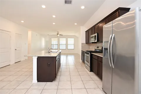 a kitchen with stainless steel appliances granite countertop a refrigerator a stove a sink and a refrigerator