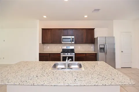 a kitchen with stainless steel appliances granite countertop a sink refrigerator and cabinets
