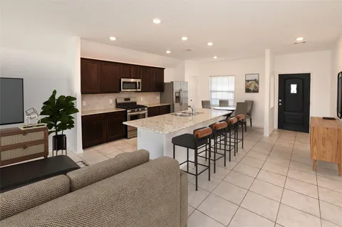 a living room with furniture a flat screen tv and kitchen view