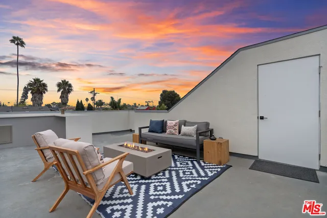 a living room with furniture two flat screen tv and kitchen view