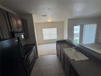 a kitchen with granite countertop a sink stove and refrigerator