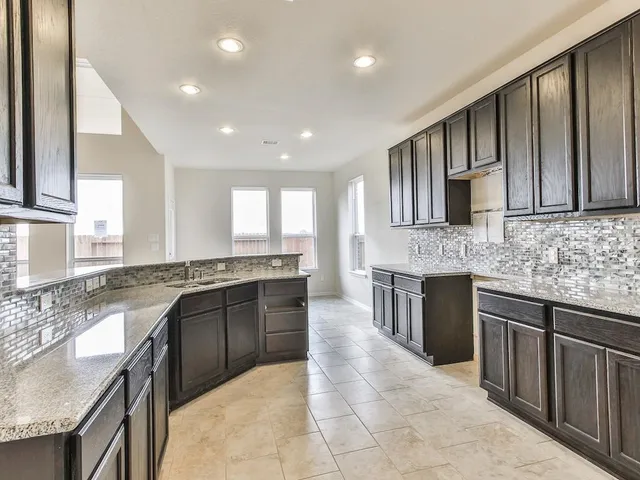 a large kitchen with stainless steel appliances granite countertop a sink stove and cabinets