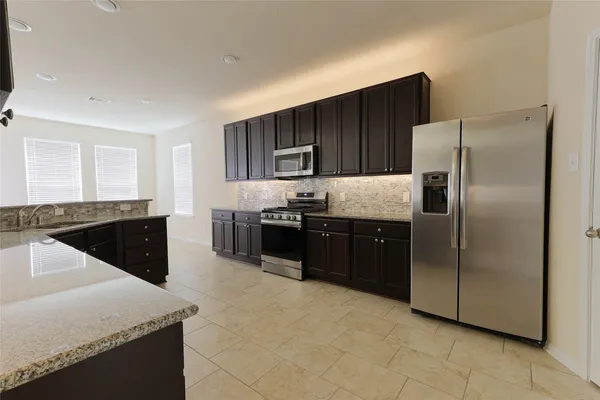 a kitchen with stainless steel appliances granite countertop a refrigerator and a sink
