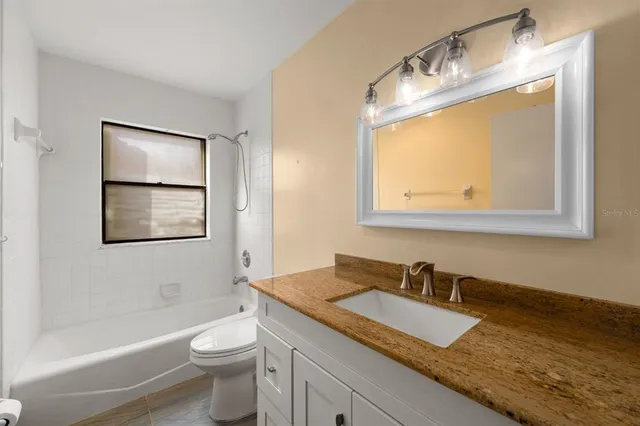 a bathroom with a granite countertop sink toilet and mirror