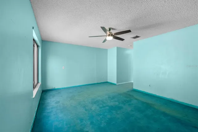 an empty room with a ceiling fan and a window
