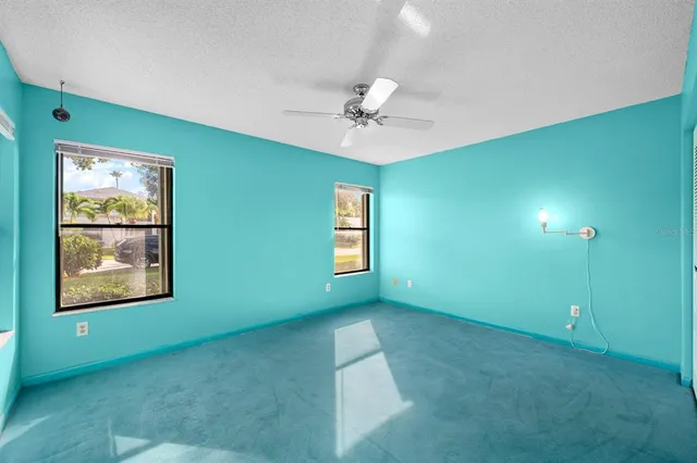 an empty room with windows and ceiling fan