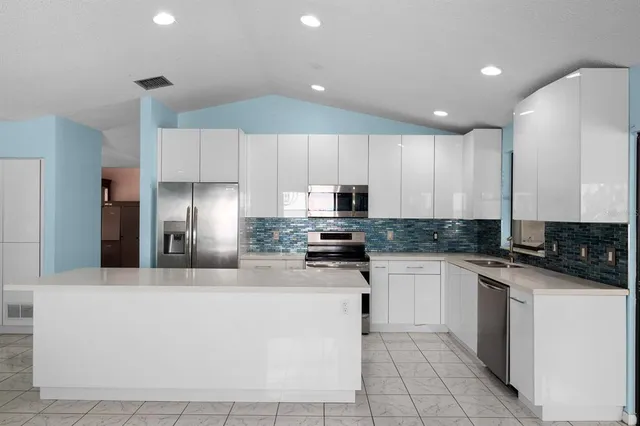a kitchen with stainless steel appliances granite countertop a stove a sink a refrigerator and white cabinets