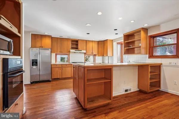 a kitchen with stainless steel appliances granite countertop a refrigerator a stove and a wooden floors