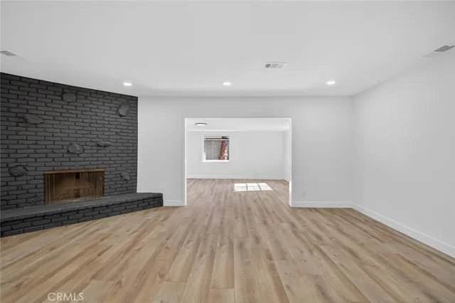 an empty room with wooden floor and fireplace