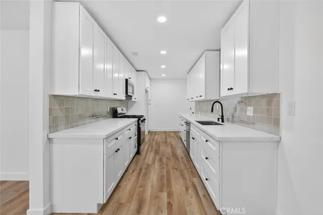 a kitchen with white cabinets appliances and sink